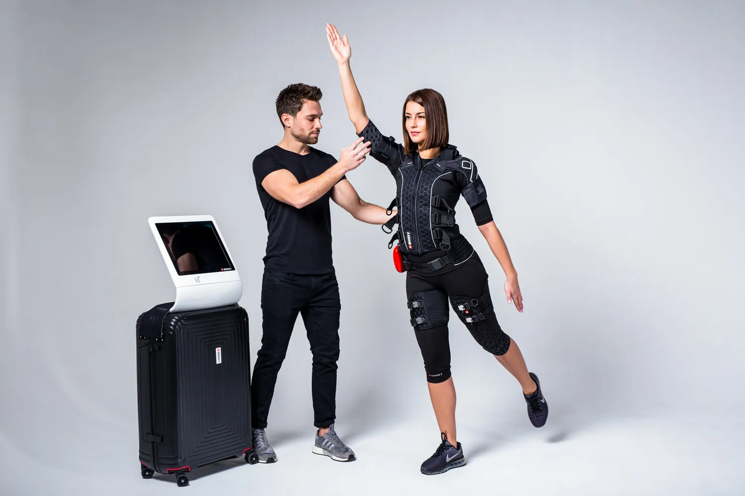 Trainer supporting a client in a black EMS suit
